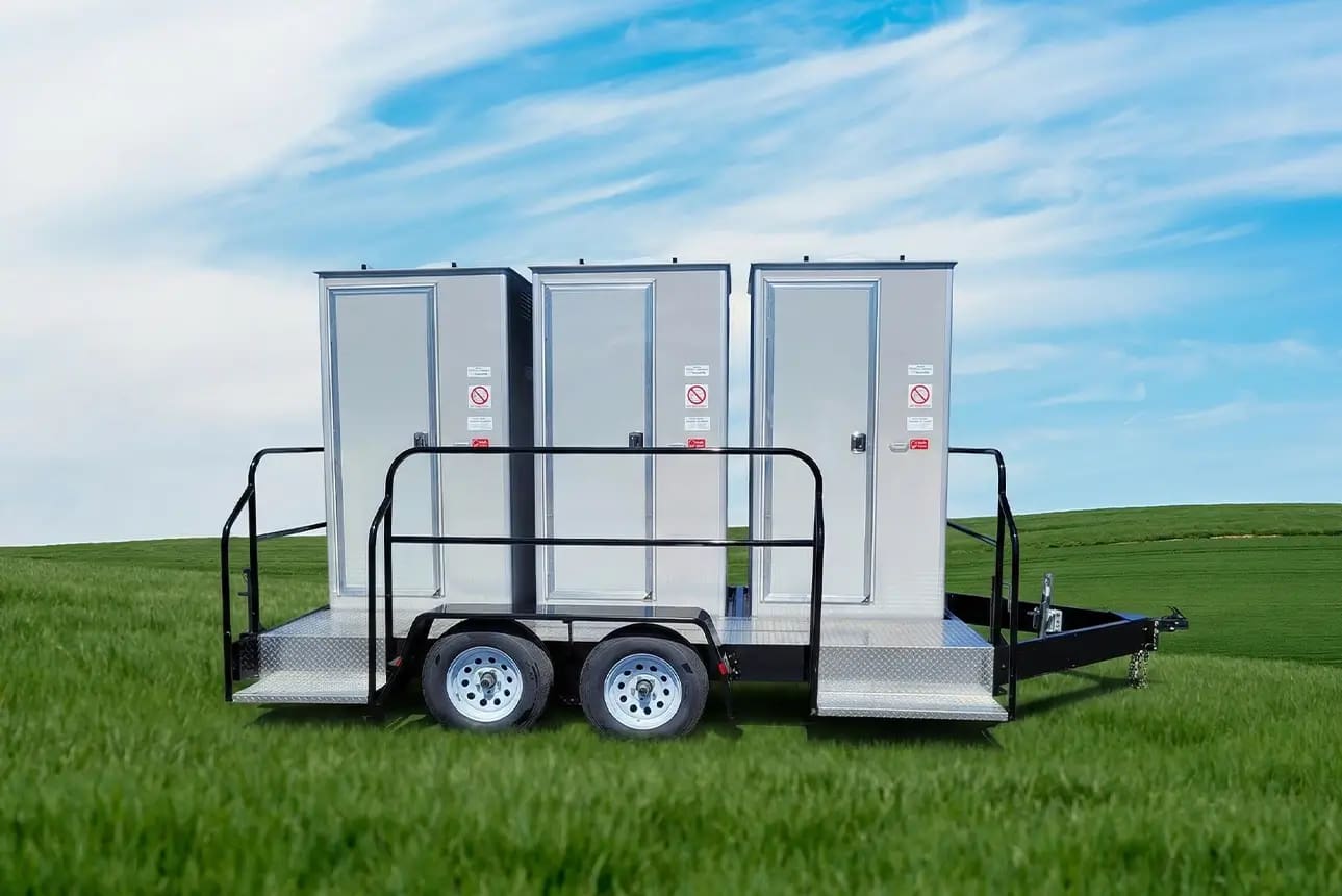 Three-stall portable restroom trailer parked on grass in Napa, CA under blue sky